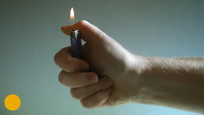 En hand som håller i en tändare som brinner, fotografi